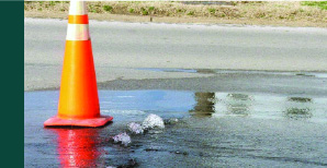 Orange pylon marking a water leak on a road.