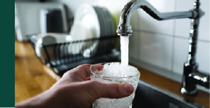 Filling a glass of water from a tap at a kitchen sink.